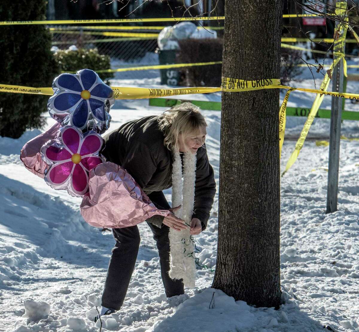 A woman, who asked not to be identified, brings a bouquet of balloons to start a makeshift memorial near the home at 158 Second Ave. on Thursday, Dec 28, 2017, the scene of a quadruple murder earlier in the week in Troy, N.Y. (Skip Dickstein/ Times Union)