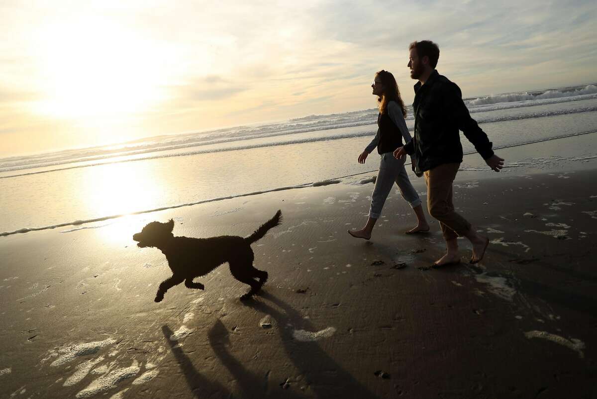 Crosby and Callie Branch walk with their dog, Foxy, at Ocean Beach in San Francisco, Calif., on Thursday, December 28, 2017.