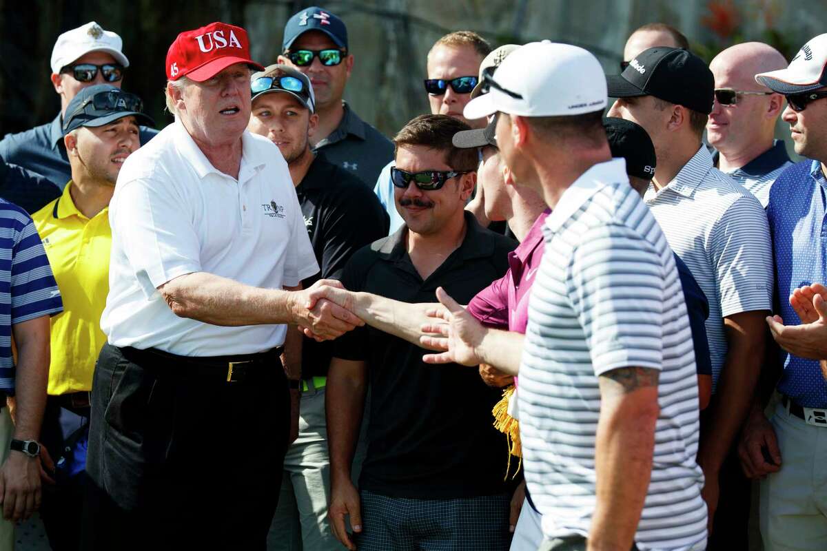President Donald Trump meets with members of the U.S. Coast Guard, who he invited to play golf, at Trump International Golf Club, Friday, Dec. 29, 2017, in West Palm Beach, Fla. (AP Photo/Evan Vucci)
