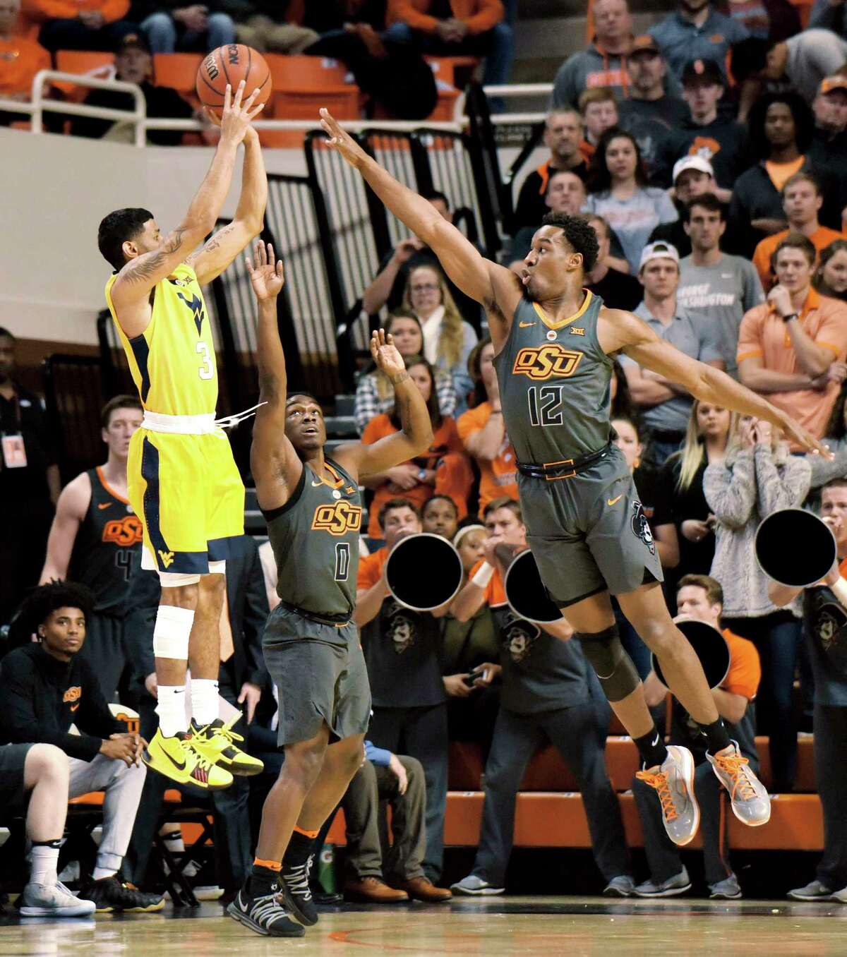 West Virginia guard James Bolden (3) takes a shot at the basket over Oklahoma State defenders guard Brandon Averette (0) and forward Cameron McGriff (12) in the first half of an NCAA college basketball game in Stillwater, Okla., Friday, Dec. 29, 2017. (AP Photo/Brody Schmidt)