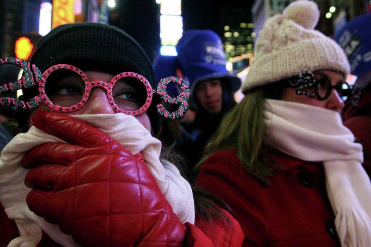 FILE- In this Dec. 31, 2008 file photo, Allison Smith of Jacksonville, Fla, left, tries to keep warm as she and others take part in the New Year's Eve festivities in New York's Times Square. Brutal weather has iced plans for scores of events in the Northeast U.S. from New Year?’s Eve through New Year?’s Day, but not in New York City, where people will start gathering in Times Square up to nine hours before the famous ball drop. (AP Photo/Tina Fineberg, File)