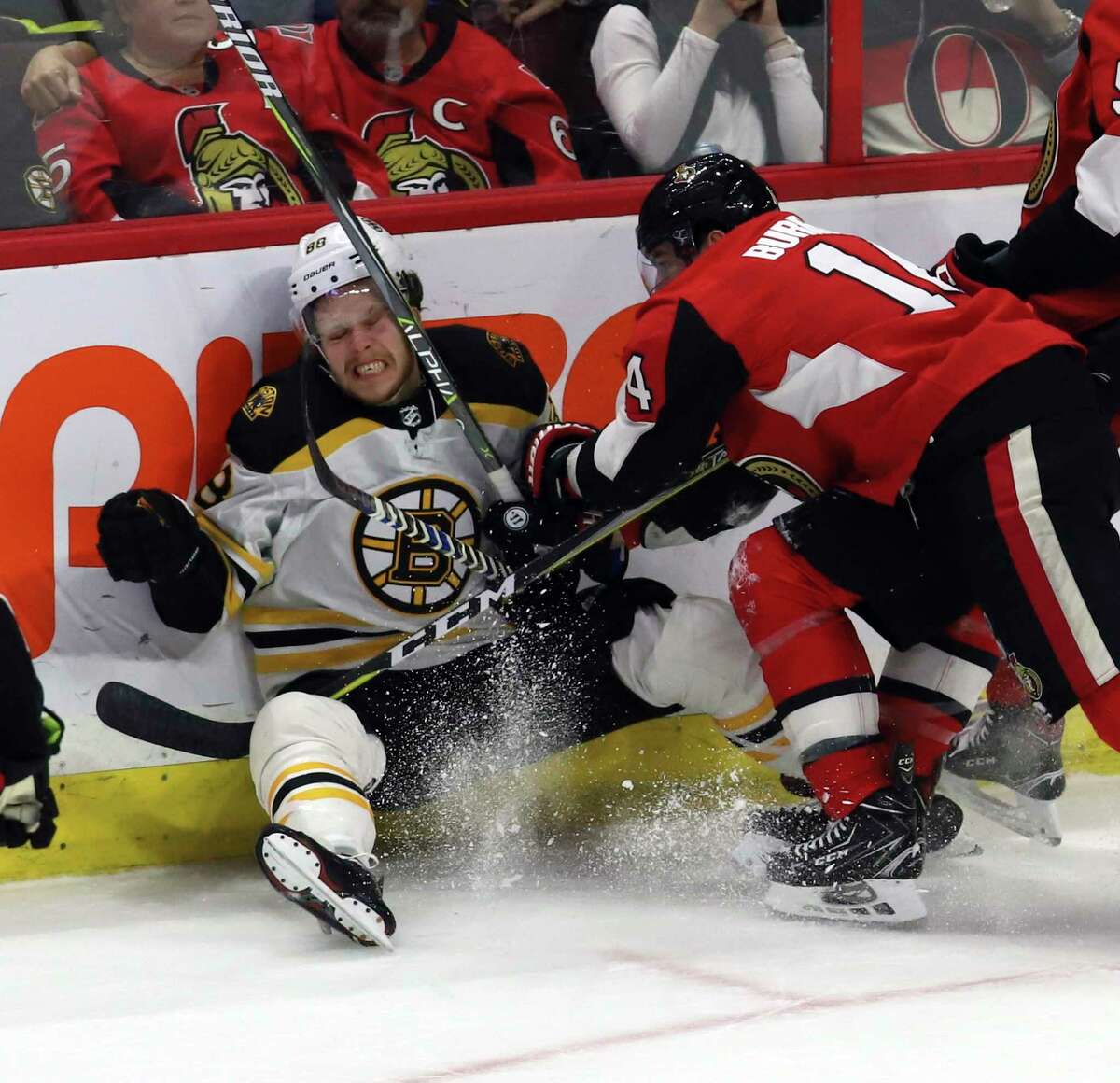 Boston Bruins' David Pastrnak (88) reacts after being checked by Ottawa Senators' Alexandre Burrows (14) during the third period of an NHL hockey game Saturday, Dec. 30, 2017, in Ottawa, Ontario. (Fred Chartrand/The Canadian Press via AP)