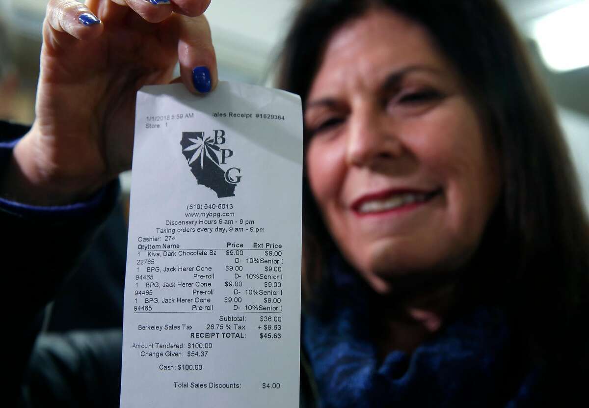 Mikki Morris holds the cash receipt for the first transaction of marijuana at the Berkeley Patients Group dispensary on the first day of legalized recreational cannabis sales in Berkeley, Calif. on Monday, Jan. 1, 2018. Morris and her husband Chris Conrad were chosen to be the first customers to buy publically at BPG.