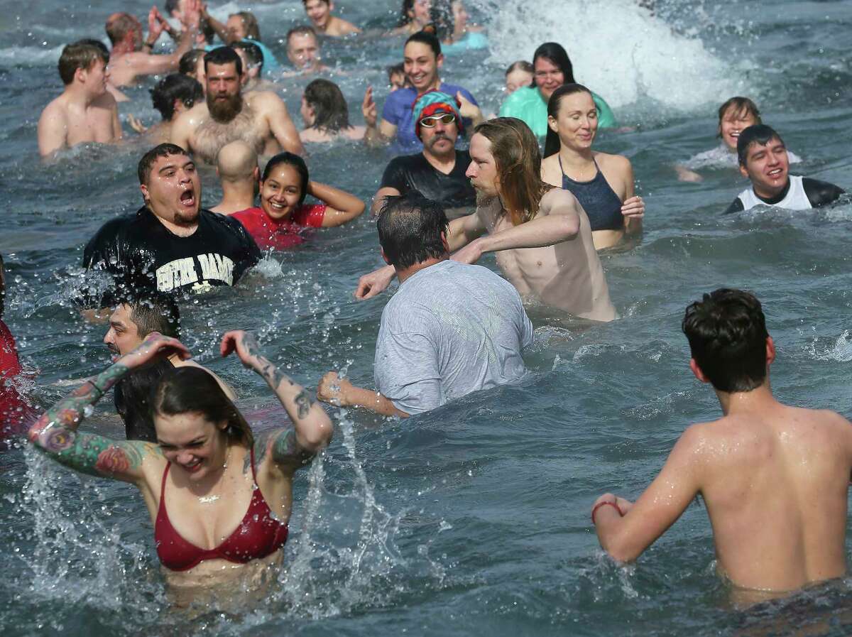 Revelers brave sub freezing temperature and wind chill to jump into the water at Sewell Park during the San Marcos River Plunge on January 1, 2018.