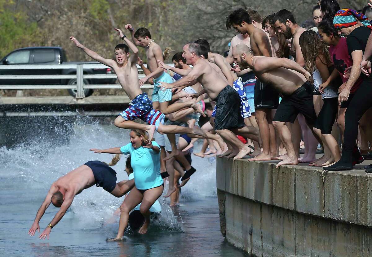 Revelers brave sub freezing temperature and wind chill to jump into the water at Sewell Park during the San Marcos River Plunge on January 1, 2018.