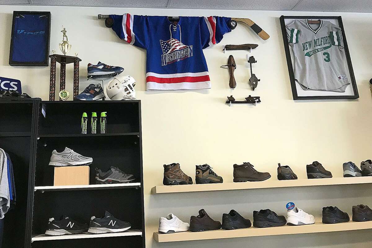 Sports memorabilia hangs on the wall above the display of hiking boots and shoes at The Athlete's Source in Bethel, Conn., on Tuesday, Jan. 2, 2018.