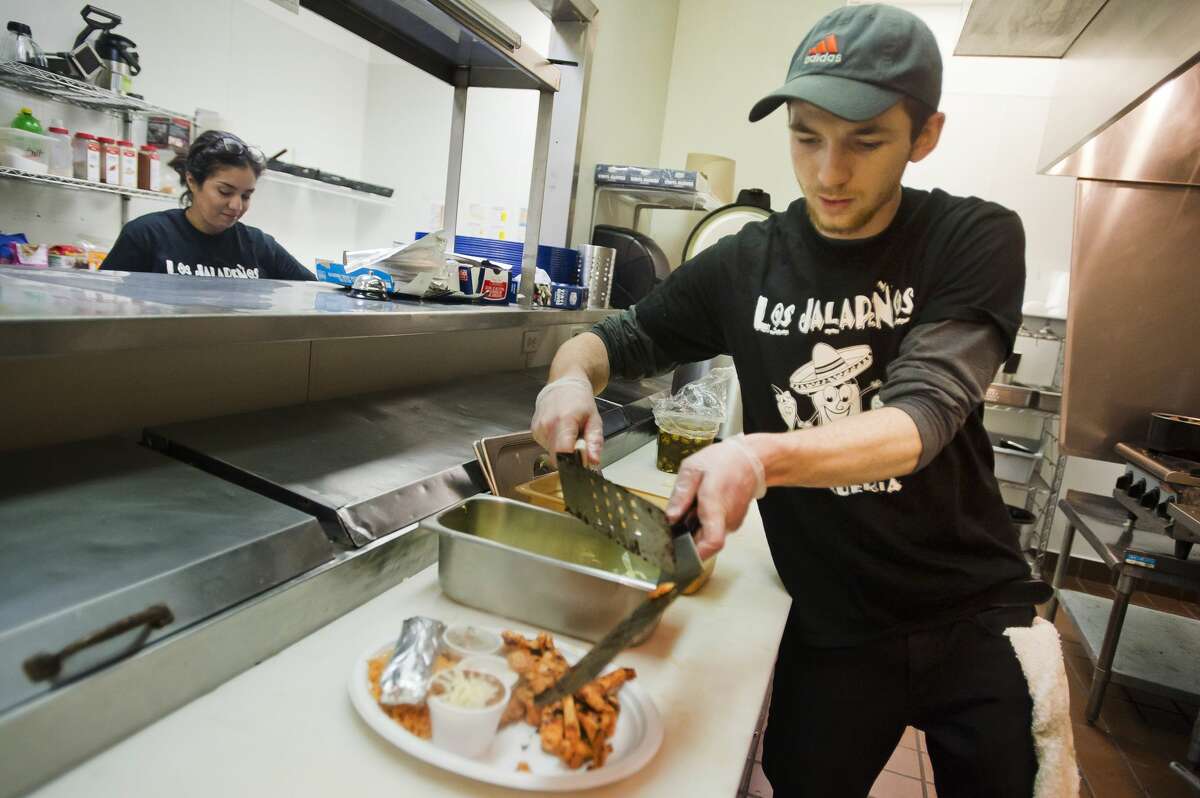 Ryan Chamberlin prepares dishes inside the kitchen of the new Los JalapeÃ±os brick-and-mortar restaurant, which is located at 1900 S. Saginaw Rd., while Mykela Finney prepares to serve customers on Tuesday, Jan. 2, 2018 in Midland. (Katy Kildee/kkildee@mdn.net)