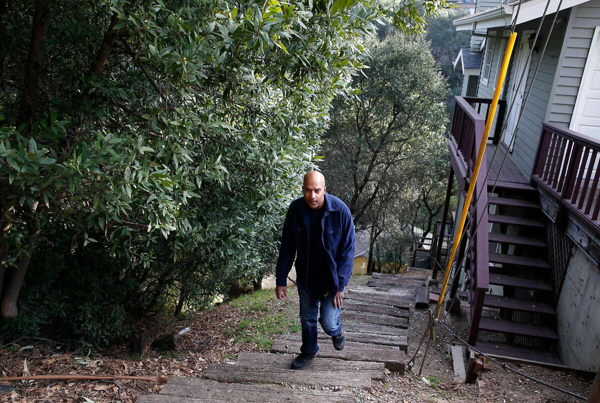 Anil Prasad climbs a staircase between his home and a grove of trees in Oakland, Calif. on Friday, Dec. 29, 2017. Prasad's insurance company informed the Oakland Hills resident they will no longer cover him for fire damage because he lives in a high-risk region. Now Prasad is looking into cutting back some of the dense foliage behind his home to ease the insurer's concern.
