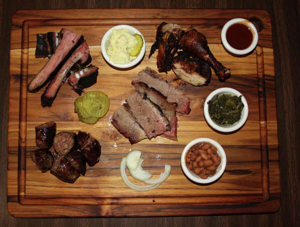 Clockwise from bottom left: house-made beef sausage, pork spare ribs, chicken and beef (brisket). Sides pictured include potato salad, mustard greens and beans at Jones Sausage & Bar-B-Que House at 2827 Martin Luther King Drive.