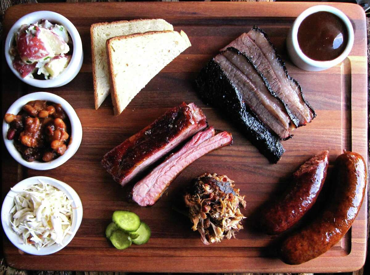 Barbecue and sides from The Granary ’Cue & Brew, including, clockwise from bottom left, cole slaw, burnt-end baked beans, potato salad, buttermilk bread, brisket, sauce, sausage, pulled pork and pork ribs.