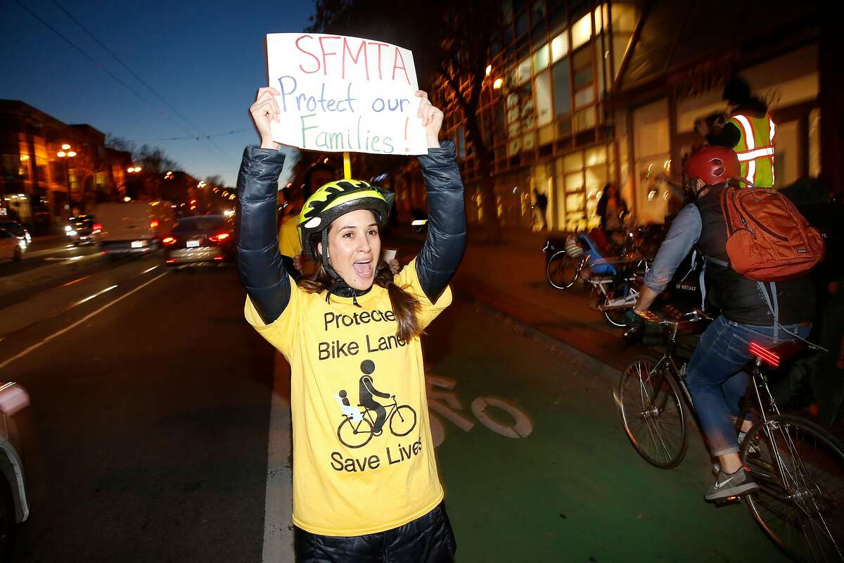 Lauren Nazario (left) of San Francisco cheers bicyclists as they ride pass while forming a "people protected bike lane" to protest the city's slowness in installing a real protected bike lane at one of the city's most dangerous intersections on Monday, December 4, 2017 in San Francisco, Calif.