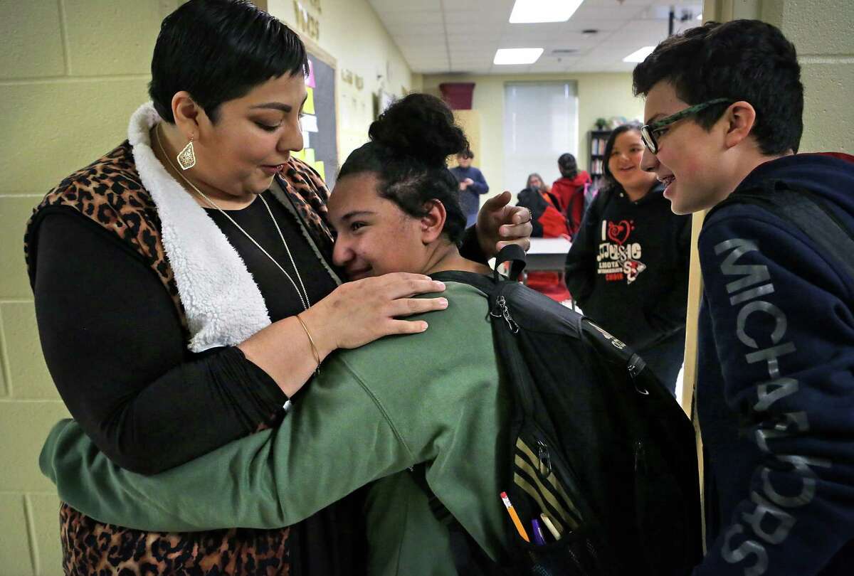 Alicia San Miguel, left, a 6th grade teacher at Losoya Intermediate School who was injured in a car accident back in September, is greeted by a tearful Reinna Harris with a hug as Joel Pichler, right, looks on. Students in all of San Miguel's classes greeted her on Wednesday, Jan. 3, 2017, her first day back to work since the accident.