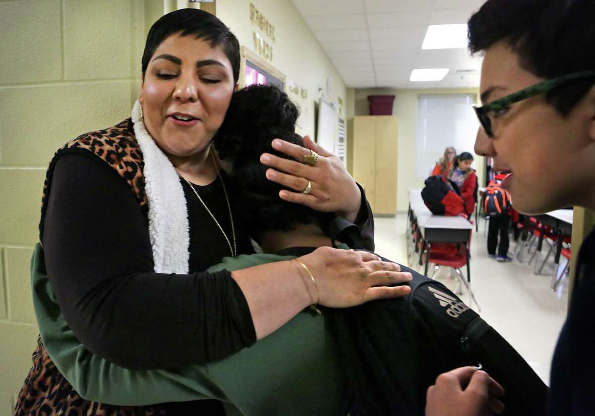 Alicia San Miguel, left, a 6th grade teacher at Losoya Intermediate School who was injured in a car accident back in September, is greeted by a tearful Reinna Harris with a hug as Joel Pichler, right, looks on. Students in all of San Miguel's classes greeted her on Wednesday, Jan. 3, 2017, her first day back to work since the accident.
