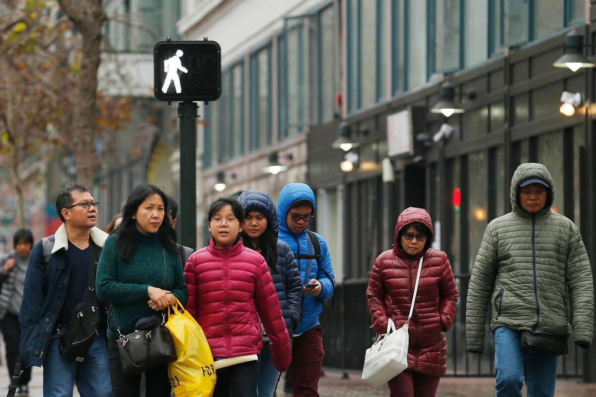 Pedestrians cross the street at Market and 6th streets, Wednesday, Jan. 3, 2018, in San Francisco, Calif.