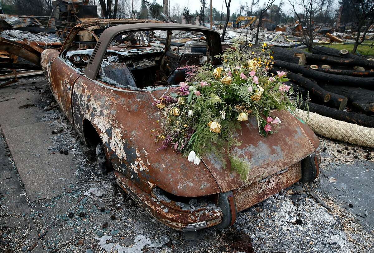 Wilting flowers are left on a charred and rusty Porsche 911 parked on View Court before a visit by Kirstjen Nielsen, Secretary of the Department of Homeland Security, for a tour of the Coffey Park neighborhood destroyed in the Tubbs Fire in Santa Rosa, Calif. on Wednesday, Jan. 3, 2018.
