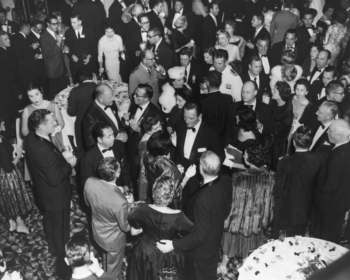 Actor John Wayne, near the center of the image facing camera with paper in his jacket pocket, attends an event in the St. Anthony Hotel as seen in this undated circa 1960 photo provided March 29, 2013, by the hotel. Wayne stayed in the hotel while doing research for the movie "The Alamo," which was released in 1960.