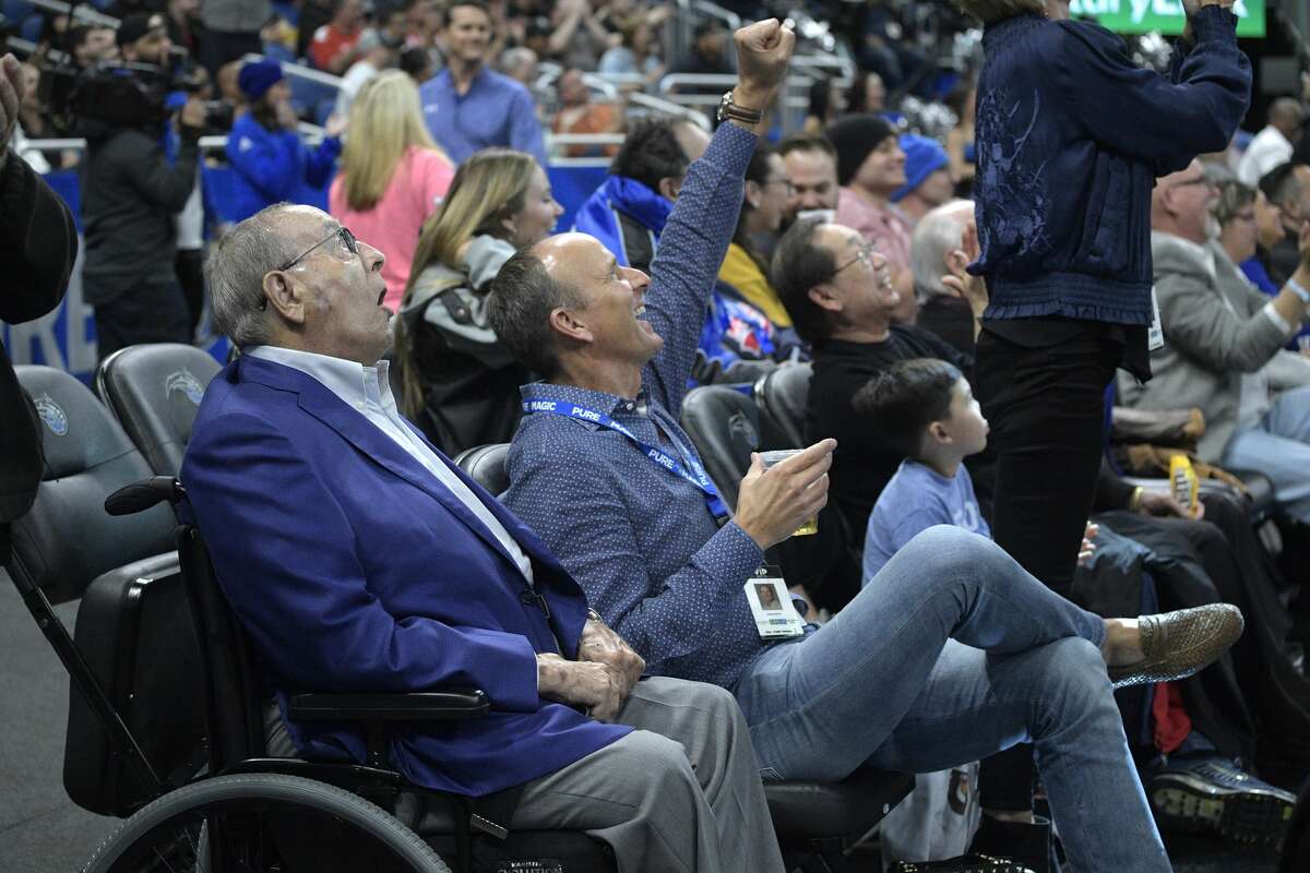 Orlando Magic owner Rich DeVos, left, and his son, Amway president Doug DeVos, center, react while watching from their court side seats during the first half of an NBA basketball game against the Houston Rockets Wednesday, Jan. 3, 2018, in Orlando, Fla. (AP Photo/Phelan M. Ebenhack)
