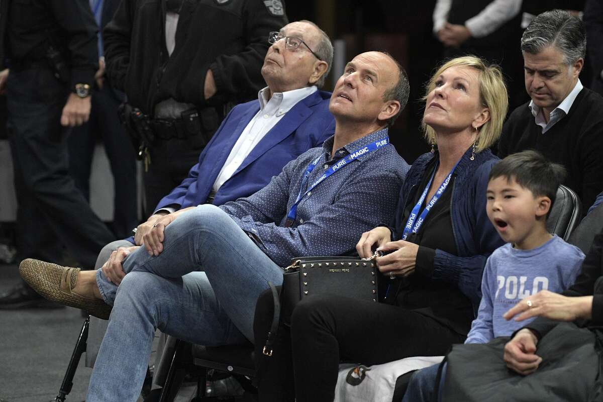 Orlando Magic owner Rich DeVos, left, his son, Amway president Doug DeVos, center, and daughter-in-law, Maria DeVos, watch from their court side seats during the first half of an NBA basketball game against the Houston Rockets Wednesday, Jan. 3, 2018, in Orlando, Fla. (AP Photo/Phelan M. Ebenhack)