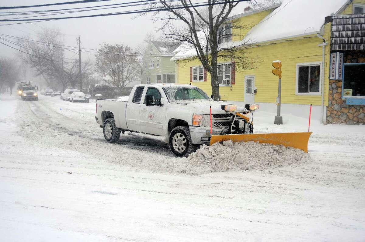 A truck with a snow plow turns from Colonial Road onto Hope Street during the snowstorm in Stamford, Conn. on Thursday, Jan. 4, 2018.