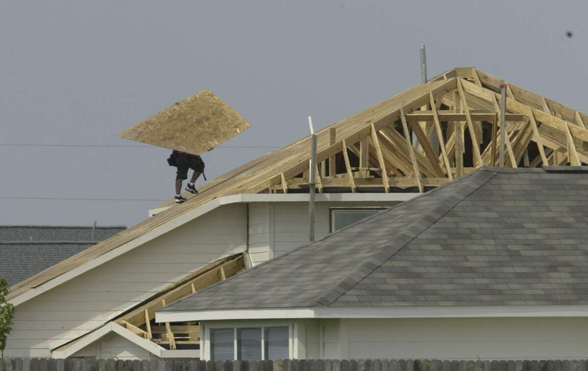A worker completes a roof in the Houston area in 2004. Today, property taxes in Texas are forcing many residents to move outside cities or their longtime neighborhoods in search of financial relief.