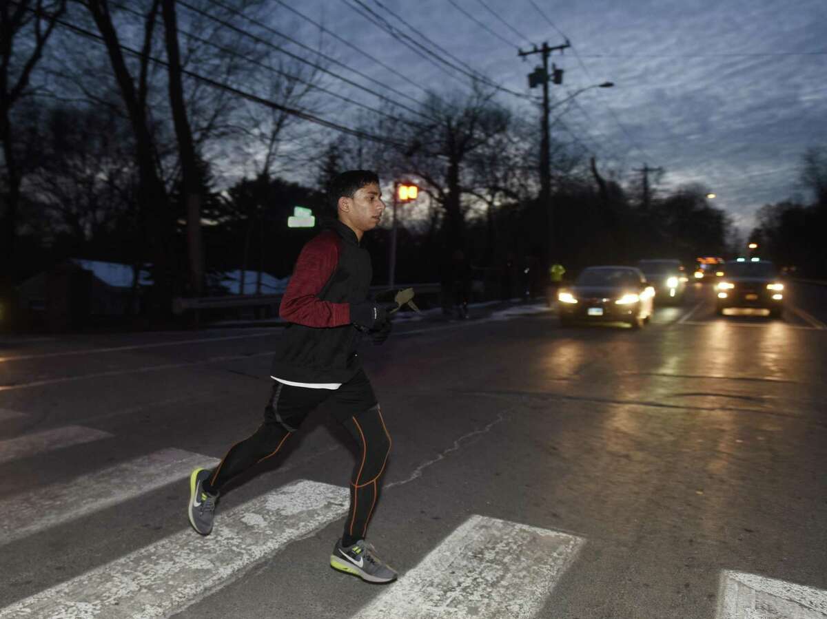 Distance runner Akash Molekudy, a junior, crosses East Putnam Avenue in the dark to finish up his training session at after-school indoor track practice at Greenwich High School in Greenwich, Conn. Wednesday, Jan. 3, 2018. Indoor track is one of the teams most affected by later start and dismissal times at GHS. Indoor track is a misnomer because students run outside, and because of the later dismissal time, now in the dark.