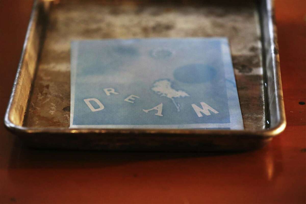 A cyanotype print with the word, DREAM, is shown in a water tray. The 2018 Brunch & Build, organized by Public Space East and community partners invited the public to unite the love of food, public greenspace, and art at Burleson Yard Beer Garden on Saturday, Jan. 6, 2018. Guests created the unique prints beside architect renderings of the Dignowity and Lockwood Park project in which the artwork will likely become part of a community collage. The event is one of many official SA300 events in conjunction with the city's Tricentennial celebration. (Kin Man Hui/San Antonio Express-News)