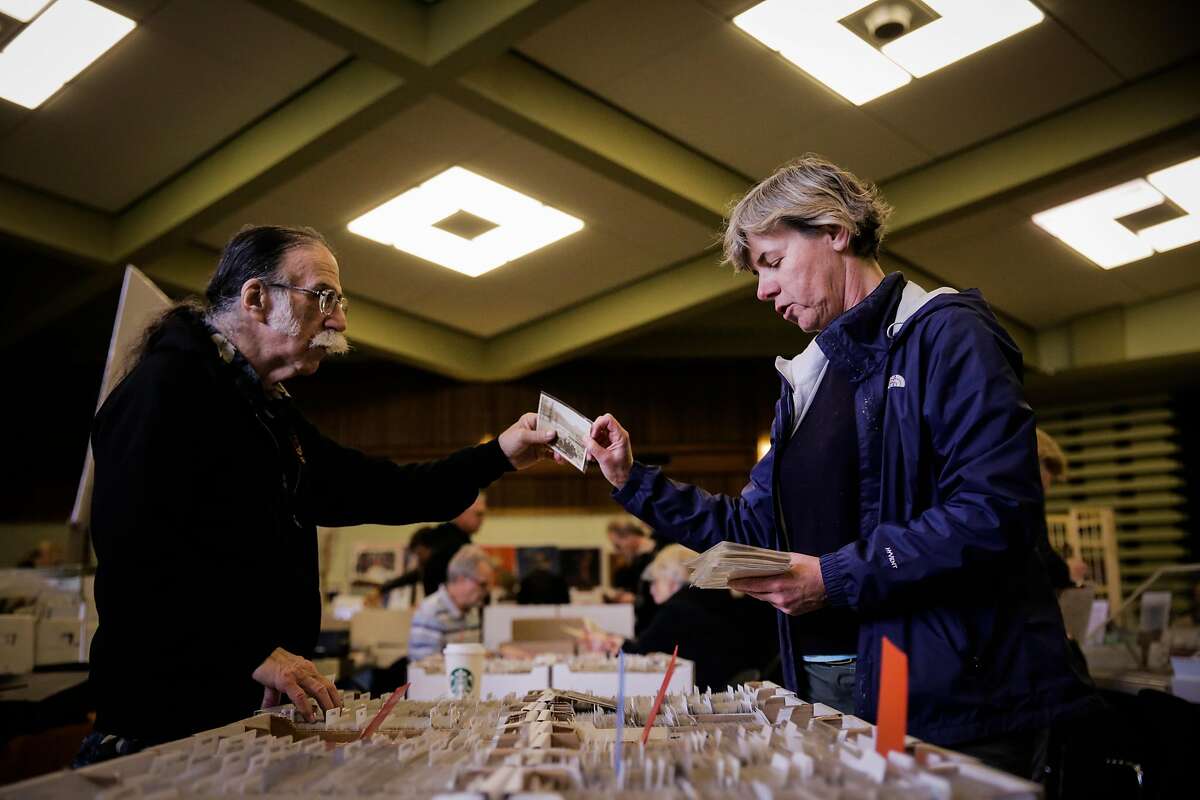 Alice Van Ommeren (right) hands Edward Henry a vintage postcard as she looks around at the Vintage Paper Fair in San Francisco, Calif., on Sunday, Jan. 7, 2018.