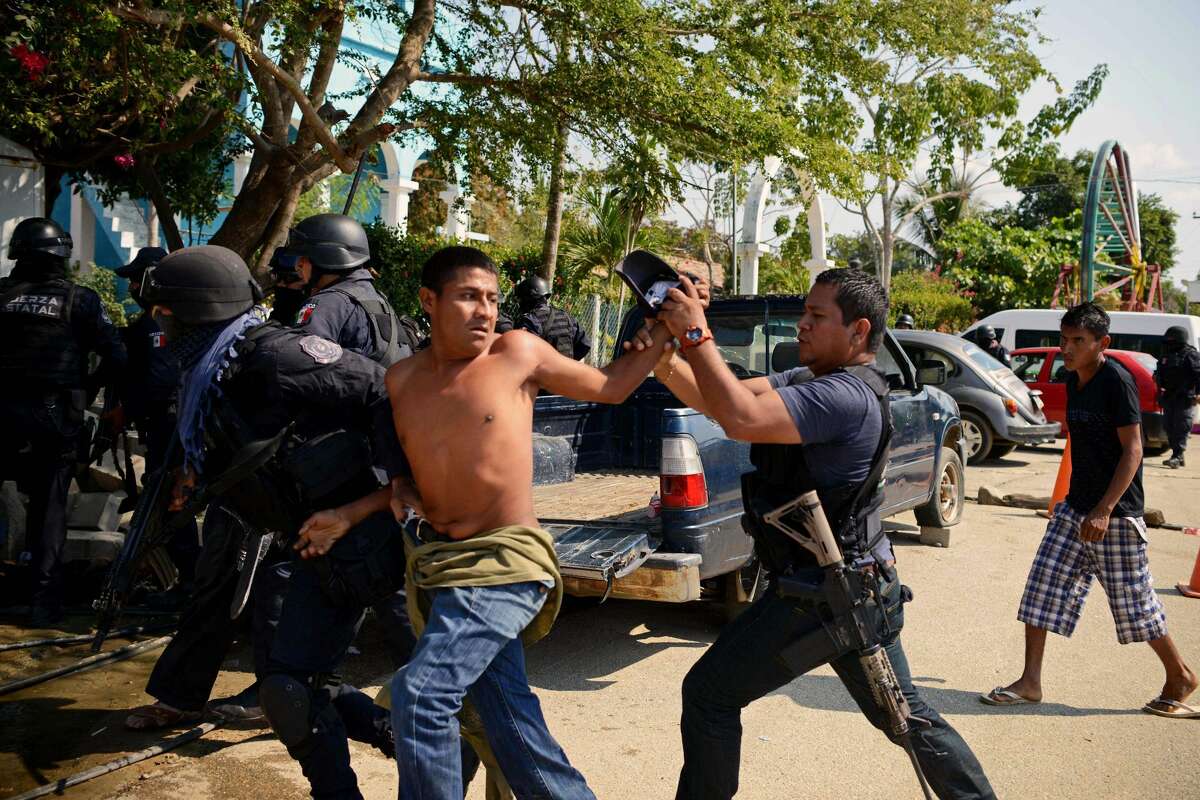 A member of the Regional Coordinator of Community Authorities (CRAC) is arrested by Guerrero state policemen after a series of clashes that has left at least 11 people dead at La Concepcion village, Acapulco municipality, in Guerrero state, Mexico, on January 7, 2018. At least 11 people were killed and 30 arrested during armed clashes among civilians, community guards and police in a rural area of Acapulco, in southern Mexico, the Guerrero government confirmed. / AFP PHOTO / FRANCISCO ROBLES (Photo credit should read FRANCISCO ROBLES/AFP/Getty Images)