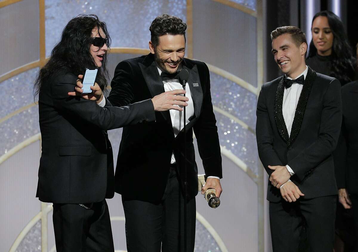 This image released by NBC shows James Franco, center, accepting the award for best actor in a motion picture comedy or musical for his role in "The Disaster Artist," as Tommy Wiseau, left, and brother Dave Franco look on at the 75th Annual Golden Globe Awards in Beverly Hills, Calif., on Sunday, Jan. 7, 2018. (Paul Drinkwater/NBC via AP)