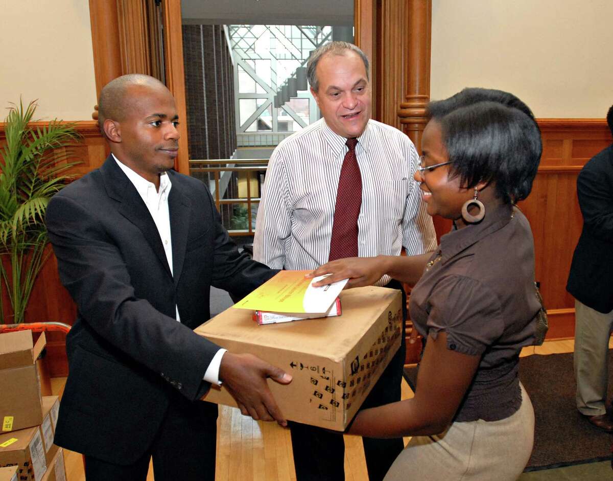 Photography by PETER CASOLINO 11/06/08 Cas081106 New Haven--17-Year-Old Gabrielle Billeps is all smiles after receiving a laptop from Che Dawson, the director of Youth Services for the City and New Haven Mayor John DeStefano, Jr., during a ceremony at City Hall. Billeps was one of 17 city youths who got laptops from the Youth@Work and Knowlege Network program for their work in a 100-hour computer training program . Photo/Peter Casolino**