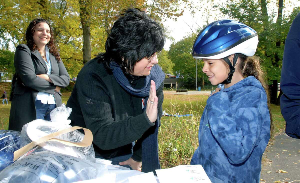 cit-street smarts-ag-10/19/08 Pina Violano (center), injury prevention coordinator for the Yale New Haven Trauma Center. looks for a 'high five' from Yael Canaan, 8, of New Haven after fitting her with a helmet at the kick off of the Street Smarts program at Edgewood Park in New Haven on 10/19/2008. At left is Yael's mother, Merav. Photo by Arnold Gold AG0282C
