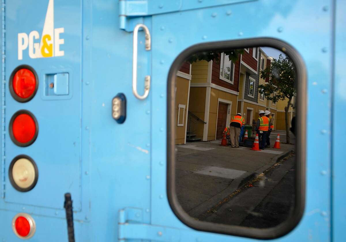 PG&E Workers are reflected in the window of one of their trucks as they inspect the scene where one of their co-workers was injured due to an electric arc accident in the Bayview area of San Francisco on Sunday, May 05, 2013.