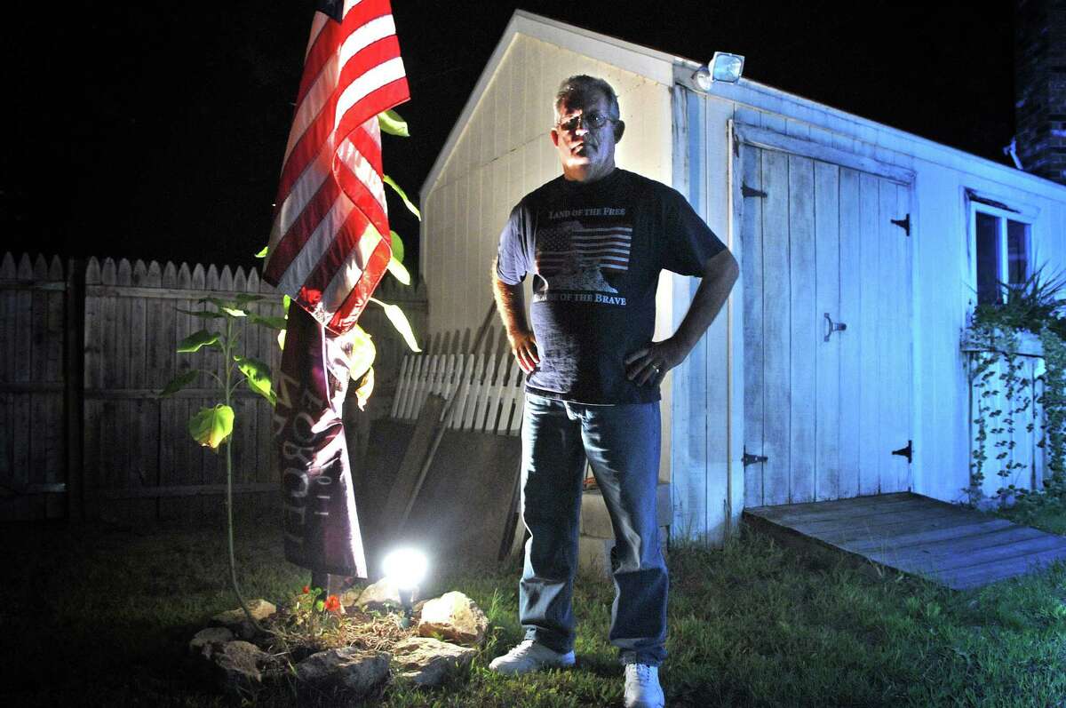 West Haven--Thomas Hackley stand next to a lit flag in his backyard. Police ticketed him and have told him to change the lighting after a complaint from a neighbor. Photo Peter Casolino/New Haven Register 09/20/2012