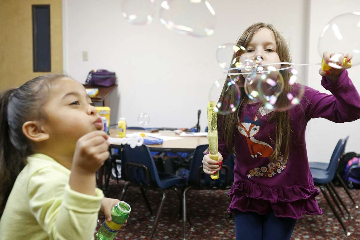 Ann Marie Becerra, 3, (left) and Emma Summers, 7, blow bubbles Monday while staying at the Lil' Roadrunners Children's Evening program.
