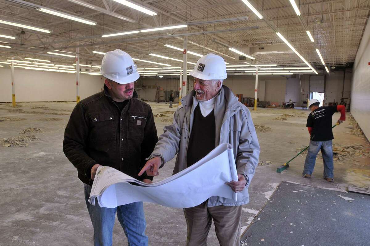 Orange-- Bryan, left, and his father, Frank Bowser look over plans for the Crunch Fitness club they are developing in a box storefront in Orange that had been vacant for years. The father/son team run PPG Properties. Photo-Peter Casolino