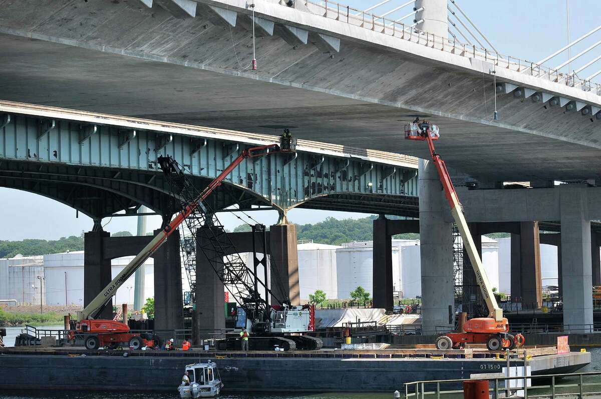 New Haven--Workers use cherry pickers off a barge under the new Pearl Harbor Memorial Bridge as they prepare to open the completed half Saturday. Peter Casolino/New Haven Register 06/21/2012
