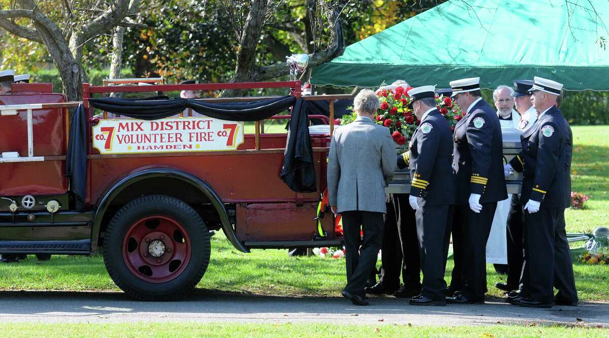 Hamden-- The casket of Duane Wetmore, Hamden Fire commissioner, is removed from a 1935 fire truck by pall bearers at Beaverdale Park during his funeral . Peter Casolino/New Haven Register. 10/15/11