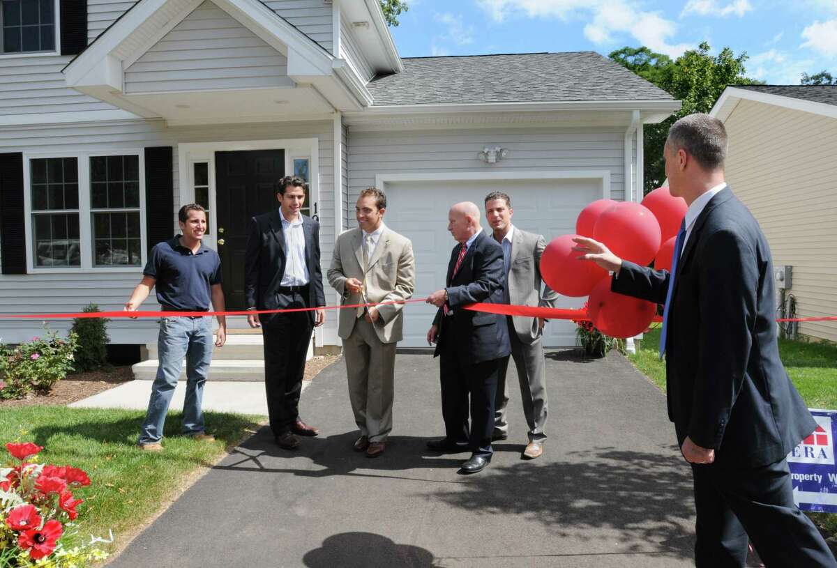 (ms091010)-Left to Right:-Anthony Massimino. Mario Massimino, Arthur Peck, and Joseph Iamunno get some advice on proper ribbon cutting techique from Attorney Michael Pinto of New Haven Economic Developement. They are showing the new homes at Redridge Preserve. Melanie Stengel/Register
