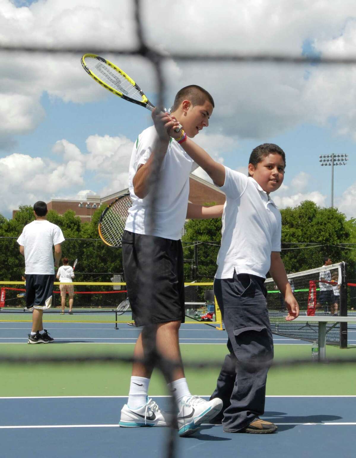 Photography by PETER HVIZDAK ph2104 #2162 New Haven, Connecticut- June 8, 2010: Tennis player Giovanni Emestica of New Haven, 18, a Career High School senior and a member of the school's tennis team, left, teaches Juan Carlos Lopez, 8, of the 4th-grade at the Fair Haven School during the annual Pilot Pen Tennis Tournament free tennis clinic for New Haven public school students from third to fifth grade . Emestica interest in tennis started at the tournament's clinic when he was in grade school.