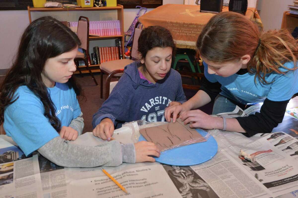 Ryan Lapatine and Alexis Rozen help Chloe Kiev with tracing her hand print in clay during an art project at Beth Israel of Westport/Norwalk Chabad, with the Circle of Friends on Sunday, Jan. 8, in Norwalk. Every month, high-schoolers volunteer to be buddies with children, teenagers and young adults with special needs through Circle of Friends, a program meant to provide social interaction.
