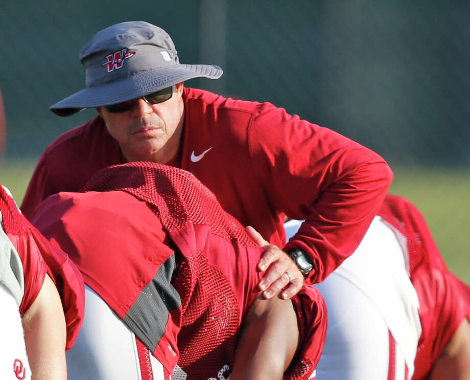 In this Tuesday, Aug. 5, 2014 photo, Oklahoma assistant coach Jerry Schmidt, top, helps a player stretch during a team practice in Norman, Okla. (AP Photo/Sue Ogrocki) Photo: Sue Ogrocki/AP