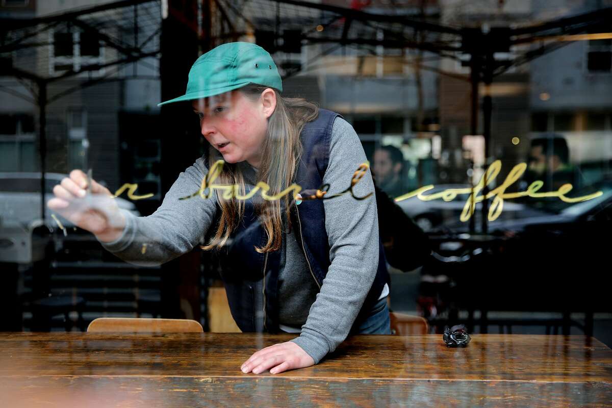 Sarah Jane Bouldin removes the Four Barrel Coffee name from the front window, Wednesday, Jan. 10, 2018, in San Francisco. Days after the S.F. Chronicle's investigative piece surrounding a sexual harassment lawsuit filed against Four Barrel and the company's founder Jeremy Tooker, the embattled coffee roaster has announced it will change its name and plans to transition into an entity that's 100 percent employee-owned. Four Barrel had announced that it would temporarily change its name to the Tide, but now it is changing it back.