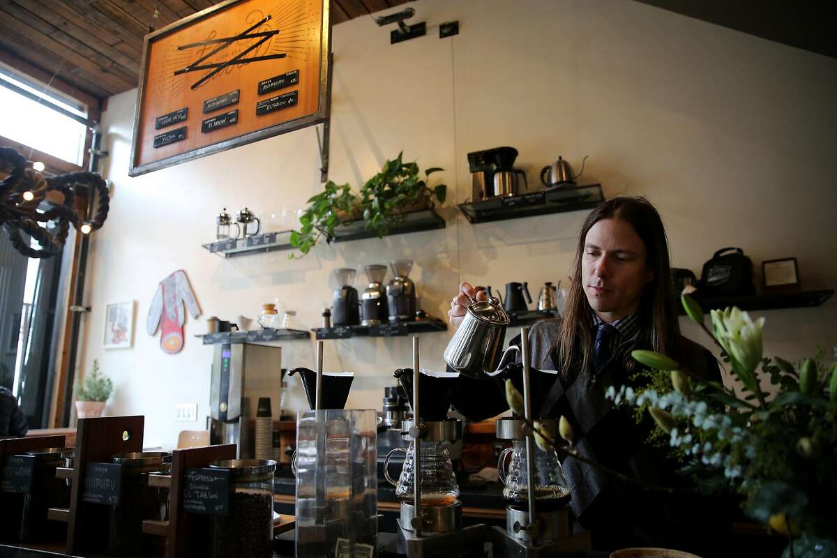 Justin Teisl, a barista and art curator, makes a customer's coffee as the name of the Four Barrel Coffee menu is seen crossed out (above), Wednesday, Jan. 10, 2018, in San Francisco, Calif.