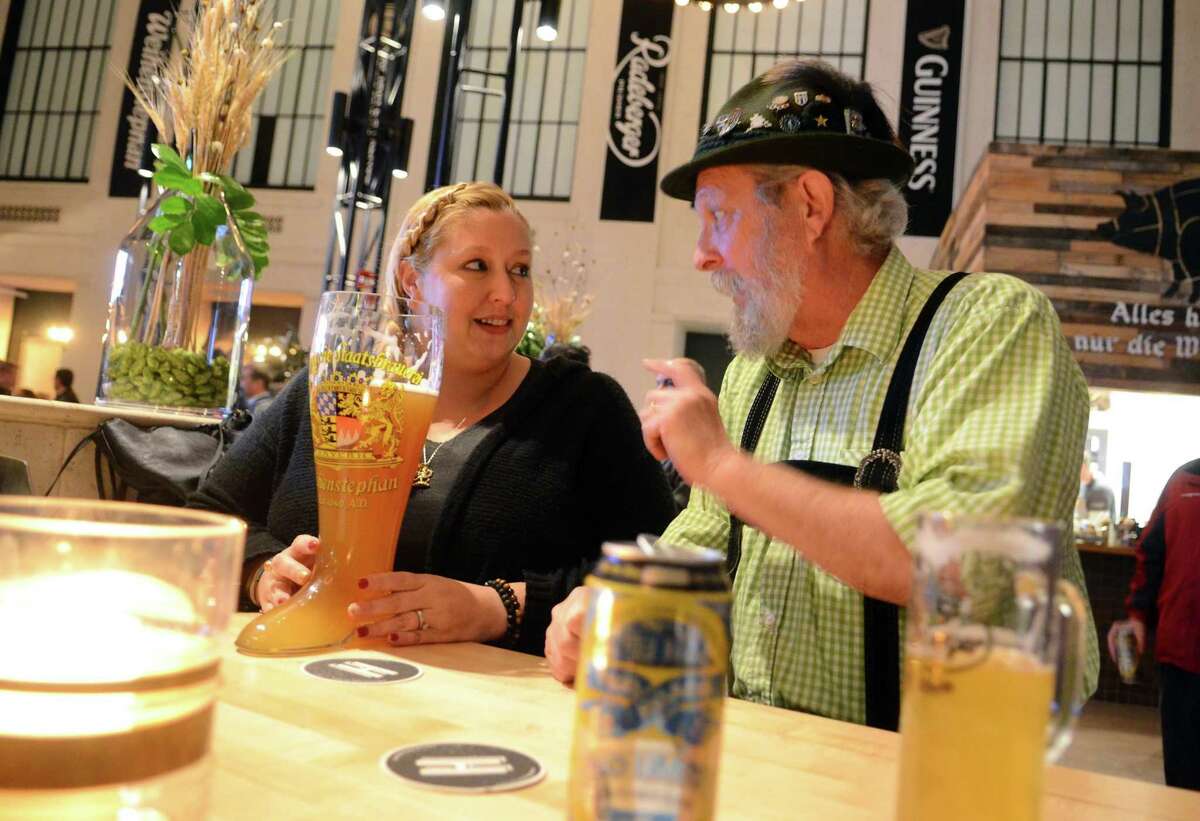Jessica Materna, of Black Rock, gets a lesson on the proper way of handling and drinking from her beer boot from Tom Fraher, of Bridgeport, during the grand opening of Harlan Haus on State Street in downtown Bridgeport, Conn., on Wednesday Jan. 10, 2018.