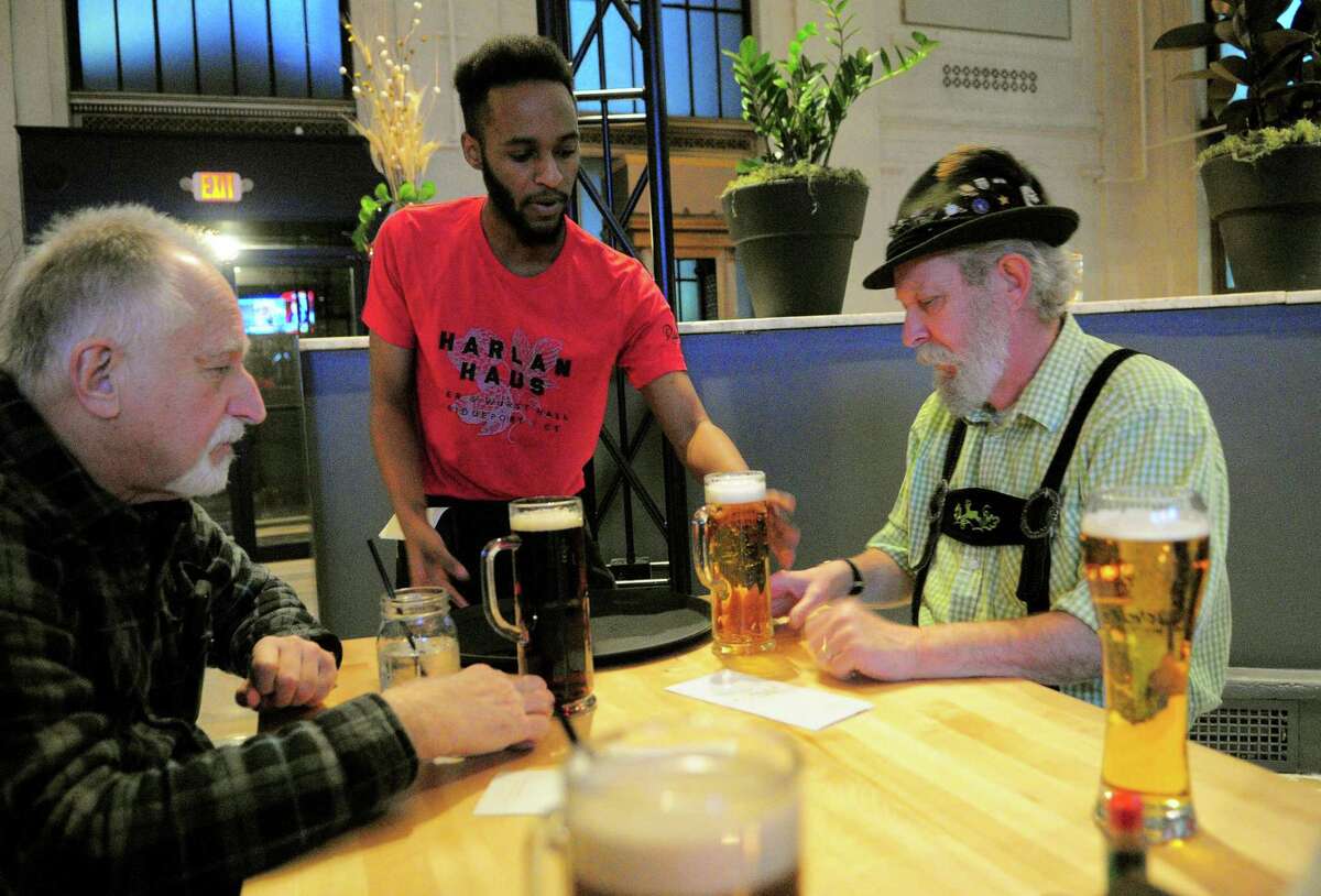 Waiter Leon Jefferson brings beer to Tom Fraher, of Bridgeport, right, and his friend Tony Longo during the grand opening of Harlan Haus, a new beer hall and restaurant on State Street in downtown Bridgeport, Conn., on Tuesday Jan. 10, 2018.