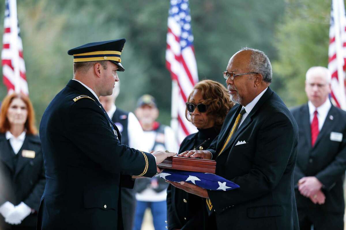 Cpt. Jeffery Hauck, left, presents the flag that was covering Pfc. Lonnie Eichelberger's coffin to his grandnephew, Cheyenne Eichelberger, right, during a funeral service at the Houston National Cemetery Wednesday, Jan. 10, 2018 in Houston. Eichelberger's remains were recently identified and returned home after he died in combat in Italy during World War II. Eichelberger enlisted in one of the only black infantry divisions as a teenager and was missing since a 1945 battle until recent dental and DNA analysis was able to identify him and 11 other soldiers from that battle. ( Michael Ciaglo / Houston Chronicle)