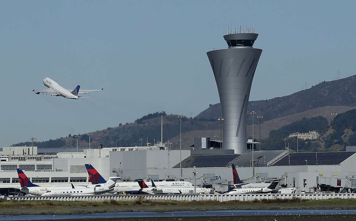 In this Oct. 24, 2017, file photo, the air traffic control tower is in sight as a plane takes off from San Francisco International Airport in San Francisco. The problem of sea level rise along San Francisco Bay is likely to be exacerbated by the sinking shoreline, a new study finds. Treasure Island is slipping nearly 3/4 of an inch per year.