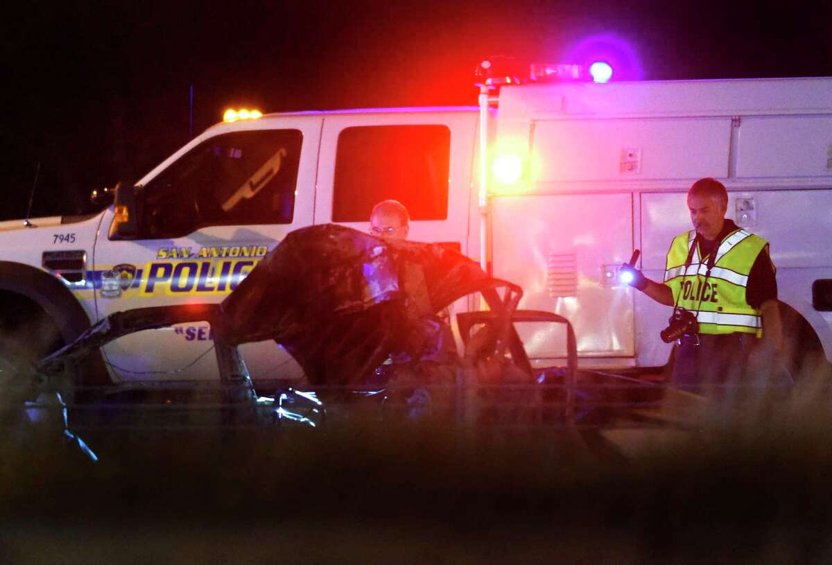 Law enforcement personnel look over the burned remains of a vehicle in which two men died on Interstate 35 near Loop 410 south of San Antonio after being struck by a truck on Wednesday night, Jan. 10, 2018. A police spokesman said that the vehicle inexplicably slowed down amid traffic when it was struck.