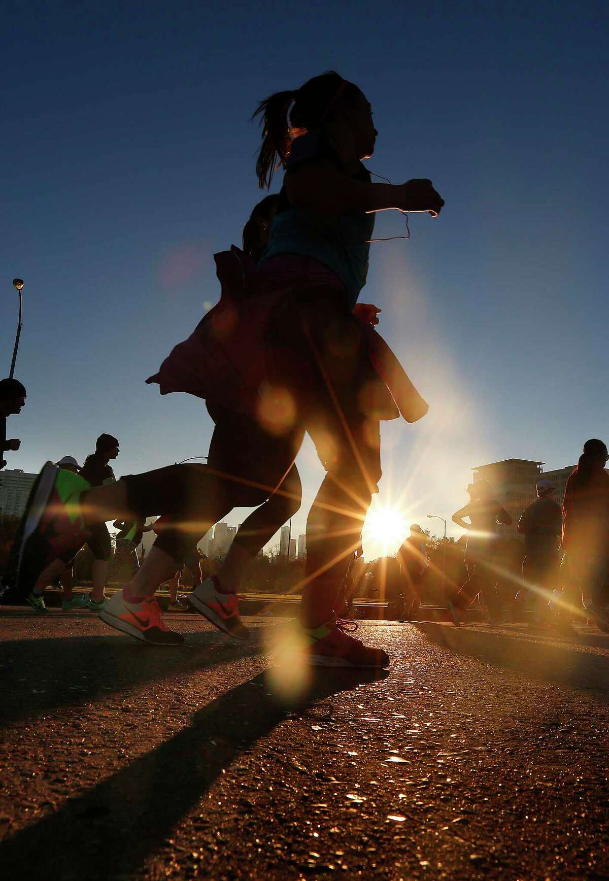 Runners cross Memorial Drive on Waugh Drive while the sun rises over downtown during the opening miles of the Chevron Houston Marathon, Sunday, Jan. 17, 2016, in Houston. ( Mark Mulligan / Houston Chronicle )