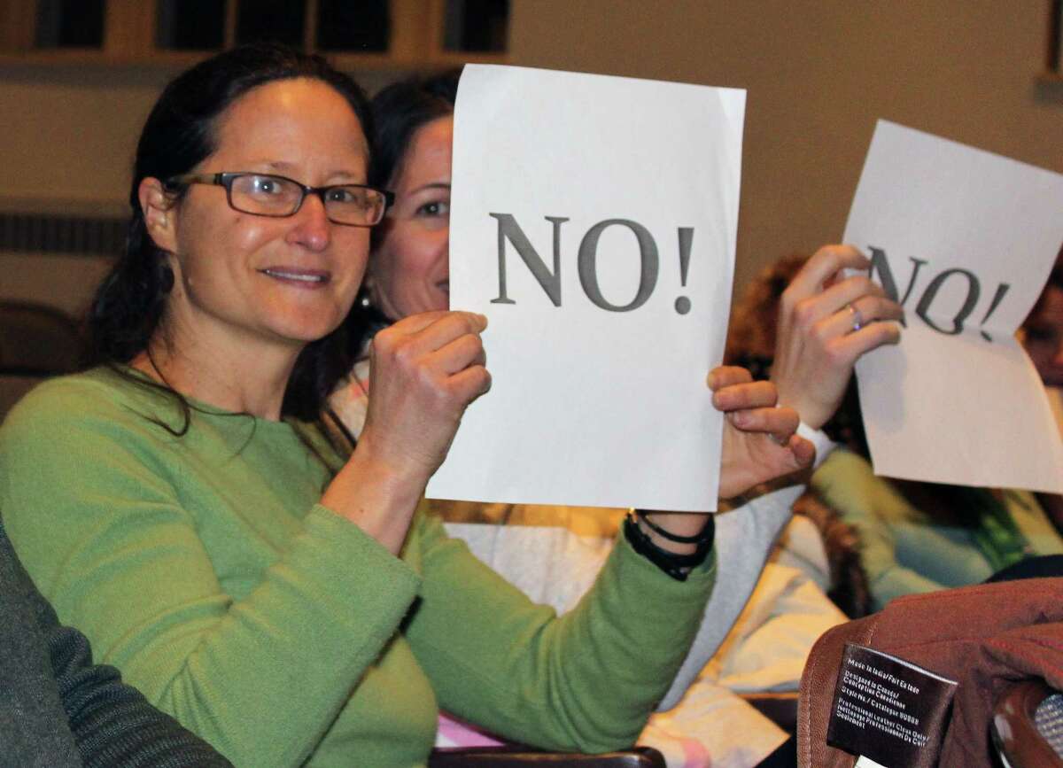 Bonnie Dubson and Anca Micu held signs at a public hearing in Westport Town Hall on Dec. 14. the two were opposing a proposed small home development at 500 Main St.